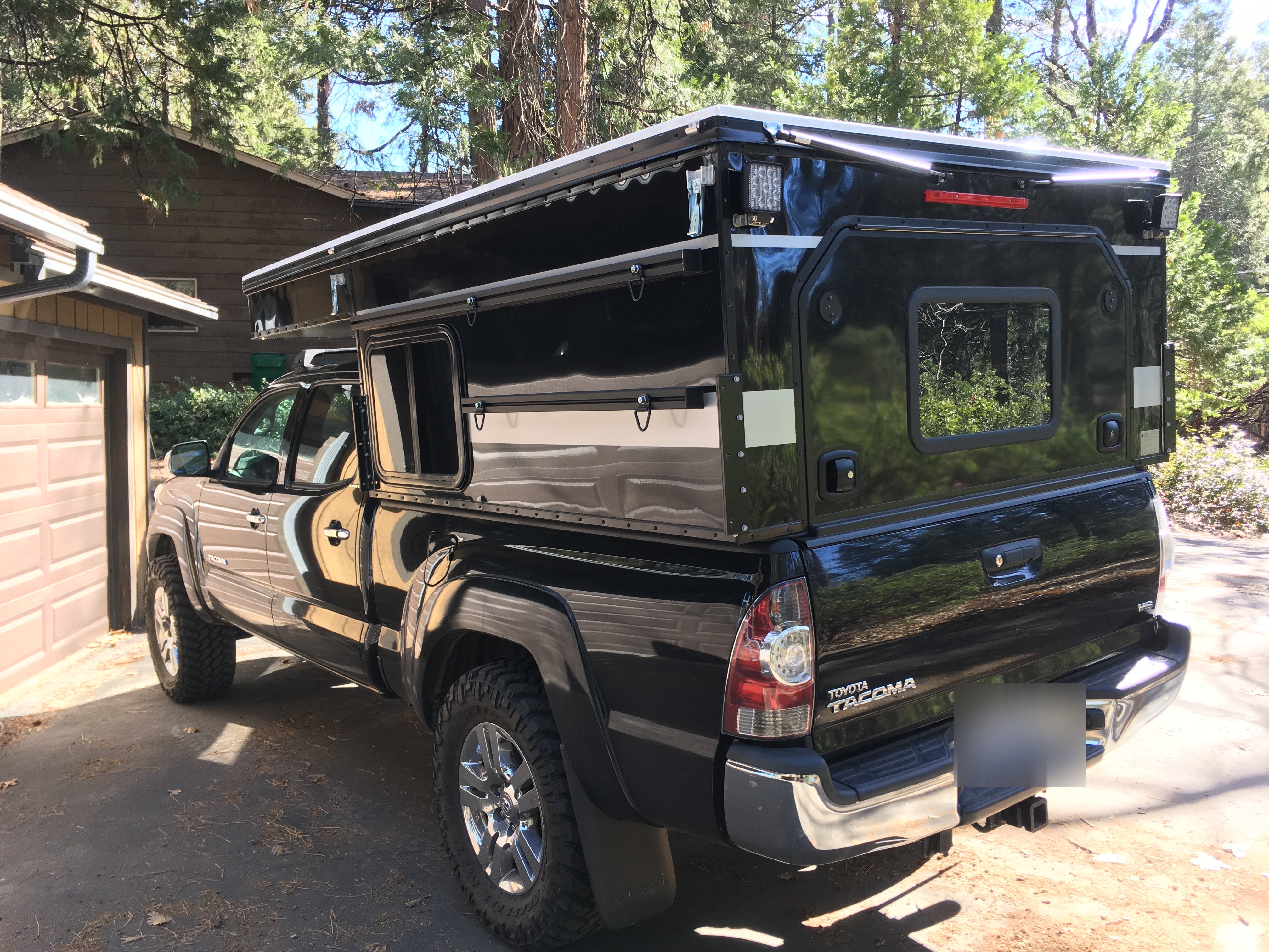 Rear view of the Four Wheel Campers Project M mounted on a Toyota Tacoma showing the pop-up design and black and silver color match
