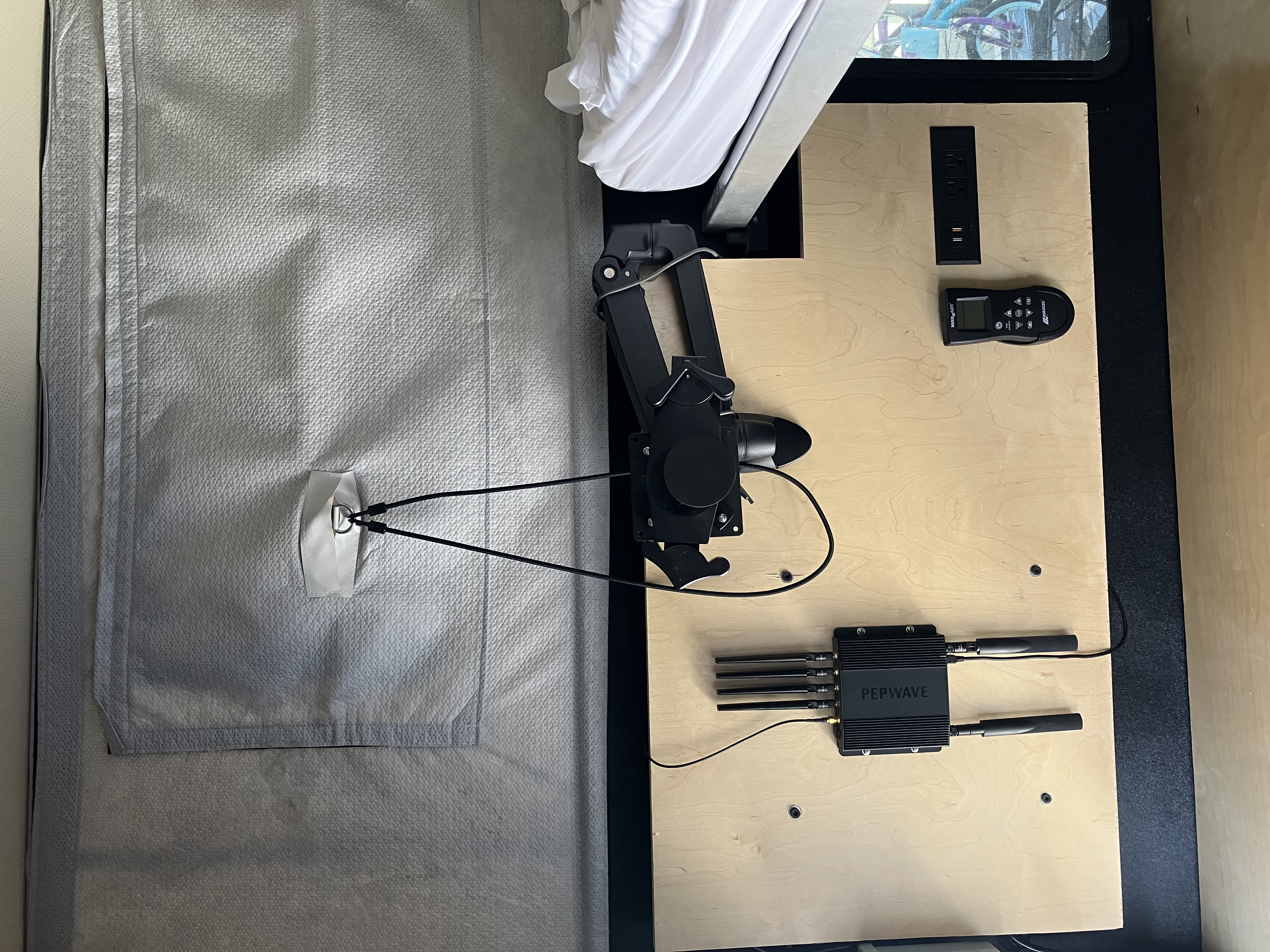 Custom L-track wall panel inside the Project M with Ergotron monitor arm, CTA Digital iPad mount, ceiling fan remote, Peplink cellular router, AC outlets and USB ports; FWC interior insulation visible behind
