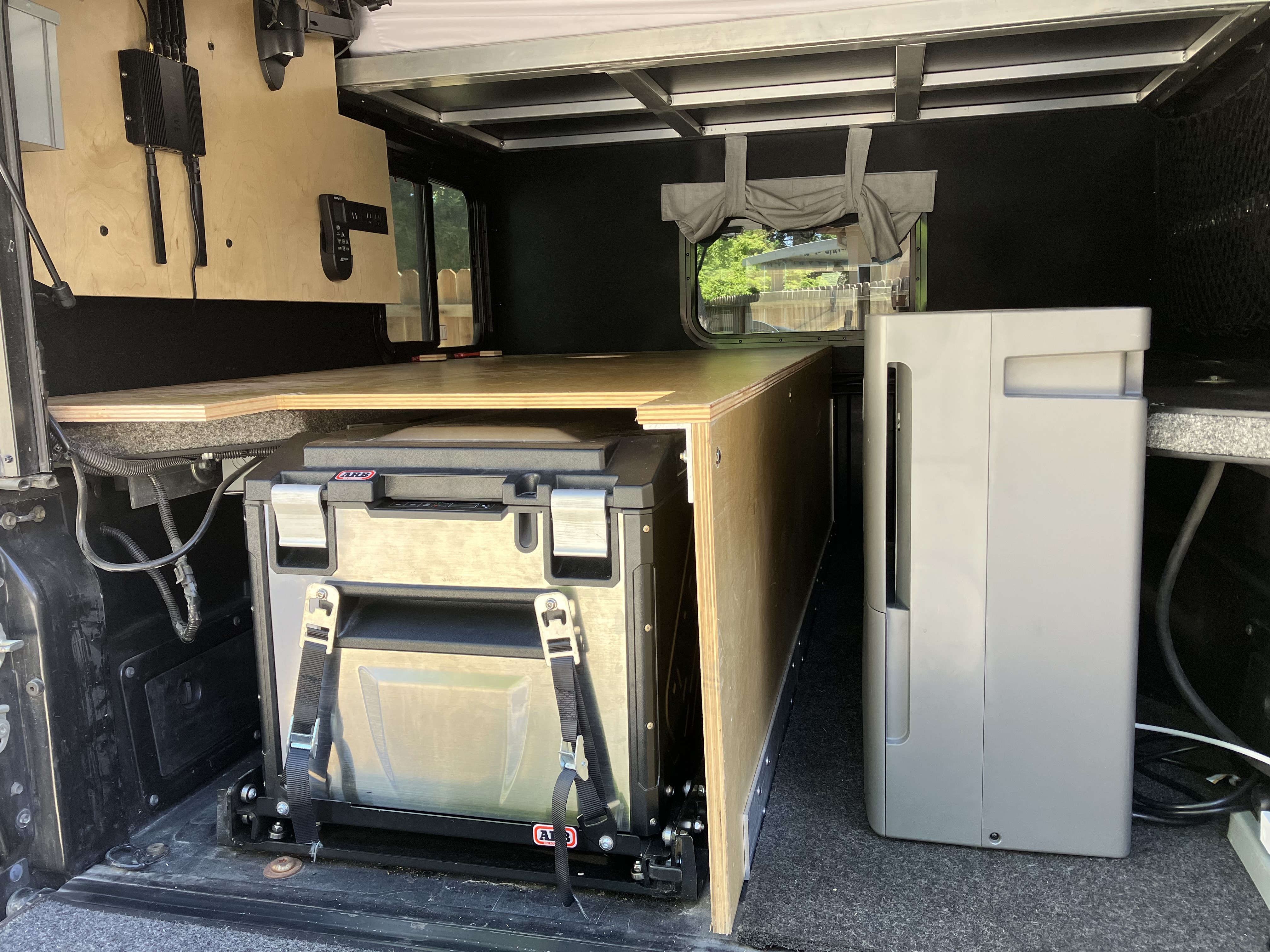 ARB Elements fridge mounted on its slide-out sled inside the Project M with the GE dehumidifier and side window visible