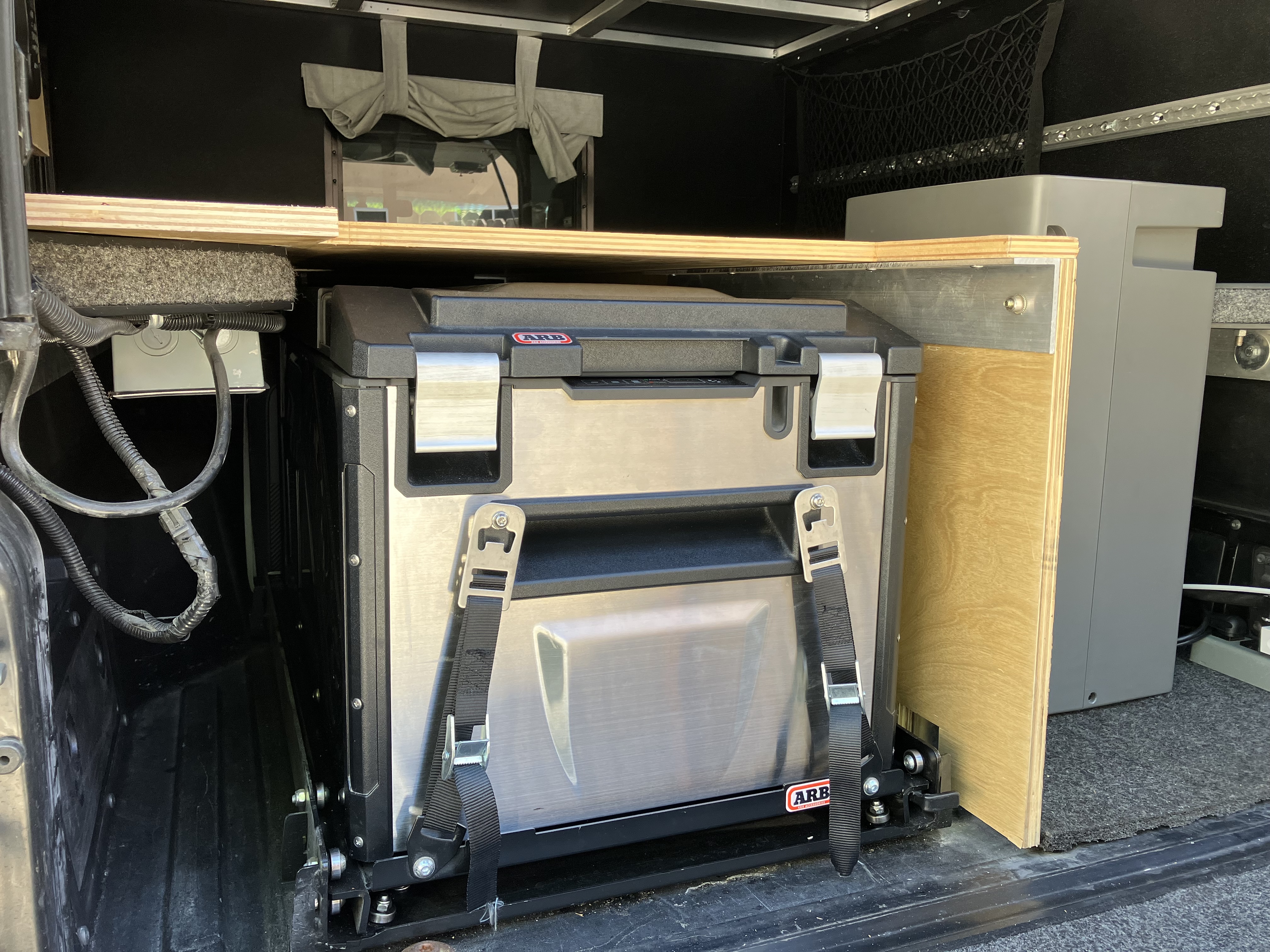 Close-up of the ARB Elements fridge fully mounted in its slide-out sled showing the heavy-duty rails and ratchet straps
