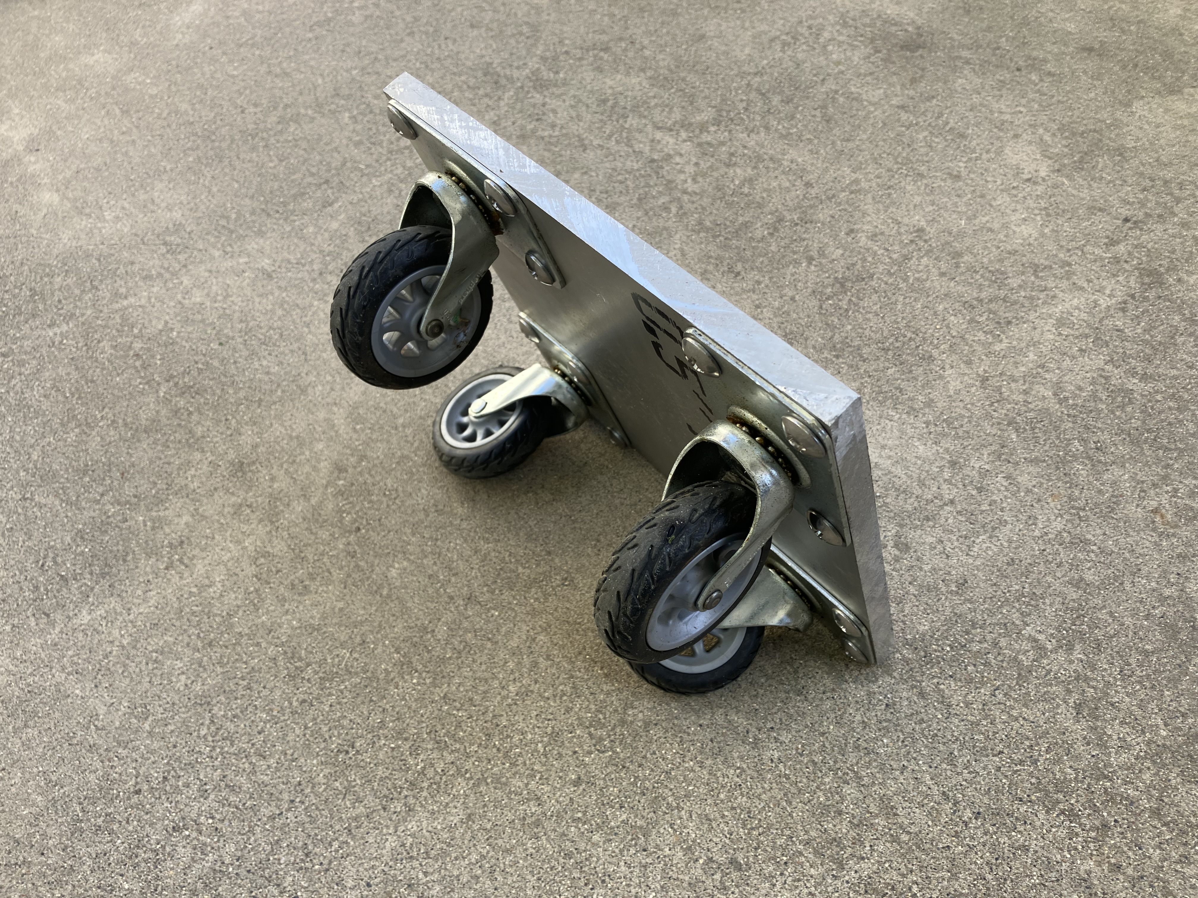 One of four custom-built corner skates showing the welded aluminum plate with four pneumatic casters used to roll the camper on and off the truck